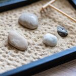 Mini jardín zen en un balcón con arena, rocas y plantas decorativas.