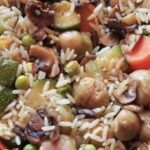 Plato de arroz al horno con verduras coloridas y frescas, receta vegana deliciosa y nutritiva.